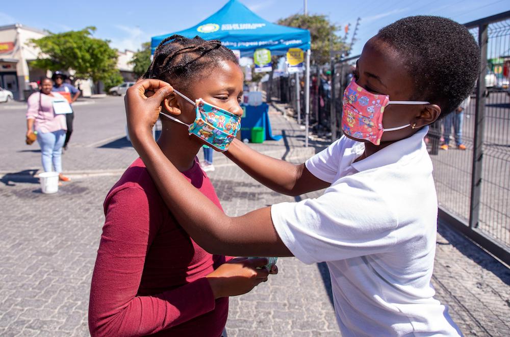 Cape Town, South Africa. 30th Mar, 2020. children put on their face masks that was donated by Mr Henri Ludski, a local printer, at a shopping centre in Makhaza, Khayelitsha, after the South African government declared a 21 day COVID-19 lockdown as part of