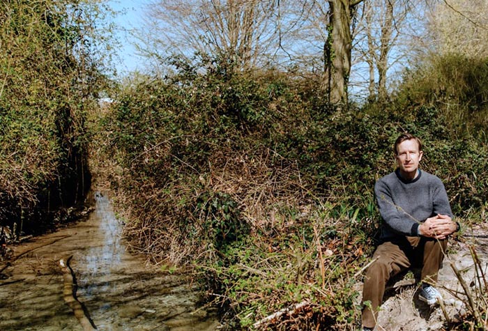 Robert Macfarlane sitting by a river side